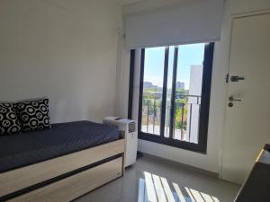 1 dormitorio con cama y ventana grande en Departamentos Mármol con Cochera en Godoy Cruz