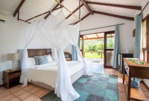 a bedroom with a bed with a mosquito net at LEMON BEACH LODGE Vilankulo in Vilanculos