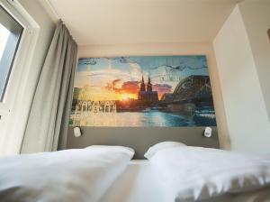 ケルンにあるB&B Hotel Köln-Cityのベッドルーム1室(ベッド2台付)が備わります。壁には絵画が飾られています。