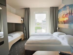 een hotelkamer met 3 bedden en een raam bij B&B Hotel Köln-City in Keulen