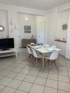 ein Esszimmer mit einem weißen Tisch und weißen Stühlen in der Unterkunft LoVi apartments Porto Palo in Porto Palo