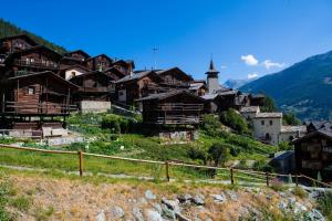 a group of wooden houses on a hill with a church at Hôtel Alpina - Swiss Ski & Bike Lodge Grimentz in Grimentz