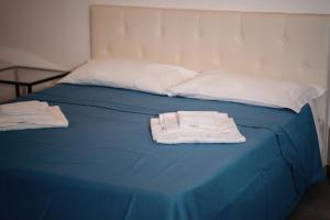ein blaues Bett mit zwei weißen Handtüchern drauf in der Unterkunft Salerno Holiday Homes in Salerno