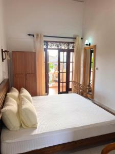 een groot bed met witte kussens in een slaapkamer bij Hummus Hostel & Restaurant in Hikkaduwa