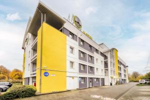 ein gelbes und weißes Gebäude mit einer Uhr oben in der Unterkunft B&B HOTEL Köln-Frechen in Frechen