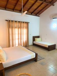 a bedroom with two beds and a window at Hummus Hostel & Restaurant in Hikkaduwa