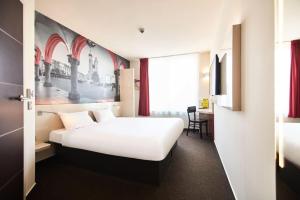 クラクフにあるB&B HOTEL Krakow Centrumの白いベッドとデスクが備わるホテルルームです。