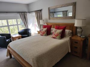 a bedroom with a bed with red pillows and a mirror at Apartments at Ballinsheen House & Gardens in Lisdoonvarna