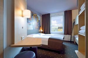 ein Hotelzimmer mit einem Bett, einem Schreibtisch und einem Fenster in der Unterkunft B&B Hotel Köln-Ehrenfeld in Köln