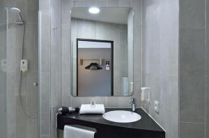 a bathroom with a sink and a mirror at B&B Hotel Köln-Ehrenfeld in Cologne