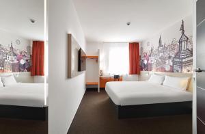 ルブリンにあるB&B Hotel Lublin Centrumのベッド2台が備わる客室で、壁には絵画が飾られています。