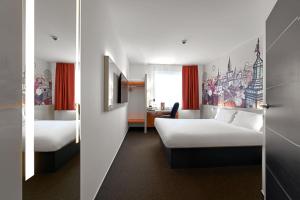 a hotel room with two beds and a desk at B&B Hotel Lublin Centrum in Lublin