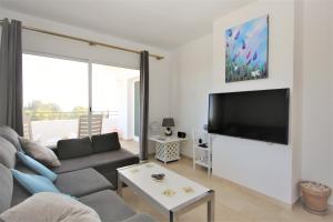 ein Wohnzimmer mit einem Sofa und einem Flachbild-TV in der Unterkunft Apartment GENOA in Estepona