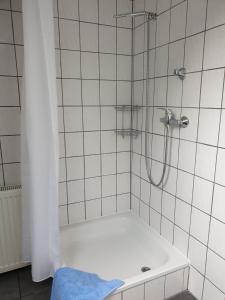 ein Bad mit einer Dusche und einer weiß gefliesten Wand in der Unterkunft Haus "Asgard" in Brinjahe