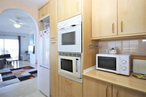 una cocina con electrodomésticos blancos y armarios de madera en Apartment GENOA, en Estepona