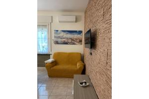 a living room with a yellow chair and a table at Pierluigi's House in Cagliari