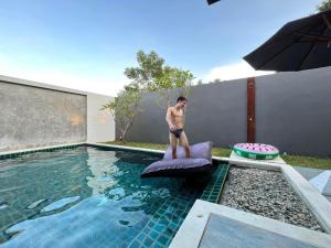 un homme debout sur un matelas à côté d'une piscine dans l'établissement Sand House, à Chaweng