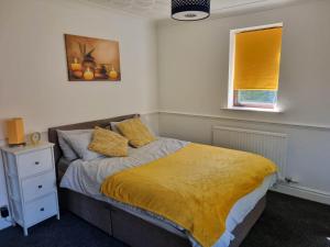a bedroom with a bed with a yellow blanket at Lovely City Studio near Station. Off Road Parking. in Norwich