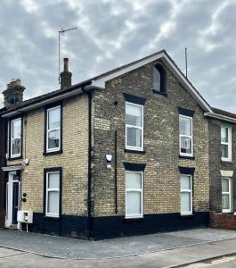 a brick building with white windows on a street at Corner Stone House - Apartment 1 in Great Yarmouth