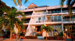 是拉差的住宿－มารินอส บีชเฮ้าส์ Marinos Beach house，一座白色的建筑,前面有棕榈树