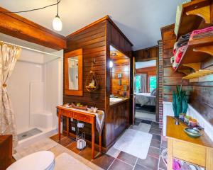 ein Badezimmer mit Holzwänden, einem Waschbecken und einer Badewanne in der Unterkunft Dragonwood Retreat 