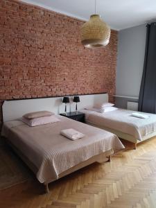 two beds in a room with a brick wall at Finger Guest Rooms in Krakow