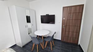 Cette petite chambre comprend une table, des chaises et une télévision. dans l'établissement Apartman Tološi 2, à Podgorica