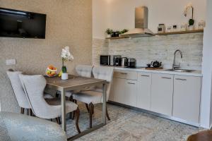 una cucina con tavolo, sedie e lavandino di Beach Walk Luxury Suites ad Ágios Nikólaos