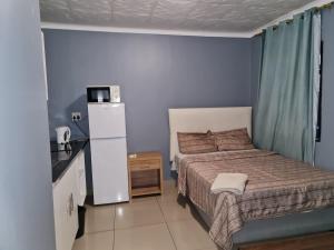 Dormitorio pequeño con cama y nevera en Hasate Guest House 10 Florence street Oakdale Belliville 7530 cape town south African, en Ciudad del Cabo