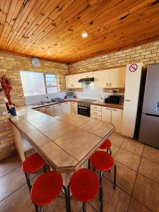 cocina con mesa con sillas rojas y nevera en Surfpoint 9, en Jeffreys Bay