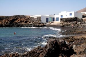 een persoon die zwemt in de oceaan bij een rotsachtig strand bij Mar de Sal in Teguise