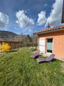 un cortile con sedie a sdraio e una casa di Petit Fare Rochois avec mezzanine a La Roche-des-Arnauds