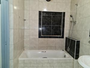 y baño con bañera y lavamanos. en Hasate Guest House 10 Florence street Oakdale Belliville 7530 cape town south African, en Ciudad del Cabo