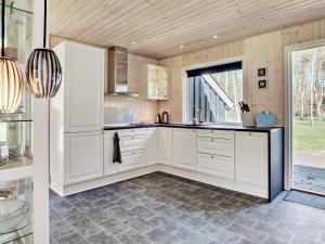 a kitchen with white cabinets and a large window at 2 person holiday home in L s in Læsø