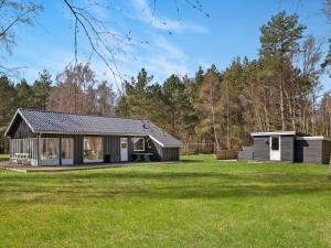 a small house in a field next to a forest at 2 person holiday home in L s in Læsø
