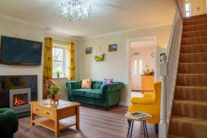 a living room with a fireplace and a green couch at Nannycroft Cottage in Beckermet