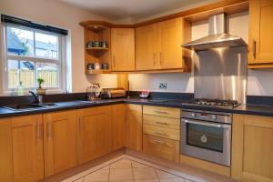 a kitchen with wooden cabinets and a stove top oven at Nannycroft Cottage in Beckermet