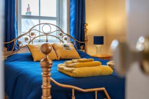 a bedroom with a bed with blue sheets and yellow pillows at Nannycroft Cottage in Beckermet