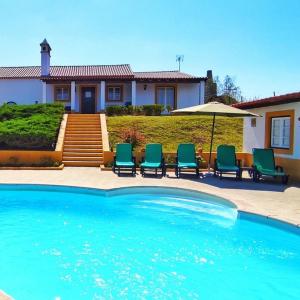 una piscina con sillas y una sombrilla junto a una casa en Castelo de Bode Monte do Valinho Country house with private pool and panoramic views, en Alverangel