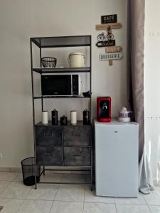 a black shelf with a microwave and a refrigerator at Au bonheur des ruelles in Monpazier