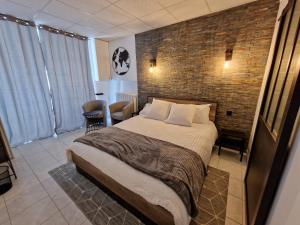 a bedroom with a bed and a brick wall at Au bonheur des ruelles in Monpazier