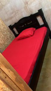 ein Bett mit roter Bettwäsche und einem roten Kissen in der Unterkunft Cabaña El Paraíso Uveros in San Juan de Urabá