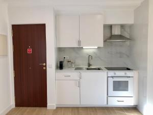 cocina con armarios blancos, fregadero y puerta en Casa Martins Country Apartment No5 en Freiria