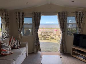 a living room with a couch and a view of the ocean at 8 Berth Luxury Caravan With A Full Sea View In Suffolk Ref 20276bs in Hopton on Sea