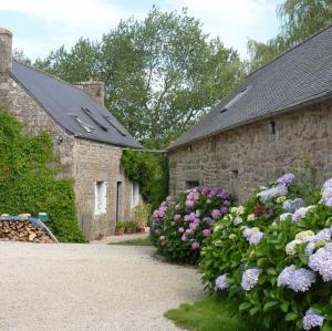 dois edifícios de pedra com flores à sua frente em Domaine de la Blanche Hermine em Plounérin
