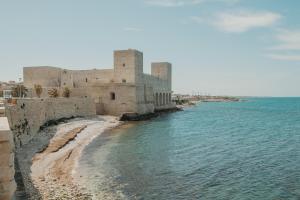 a building next to the water next to a beach at Casa Merina in Trani