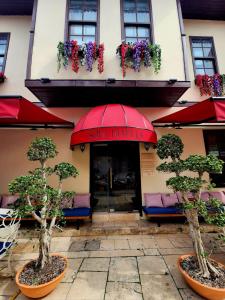 a restaurant with a red umbrella and some trees and chairs at Sofa Hotels Kaleiçi in Antalya