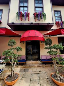 un restaurante con sombrilla roja y algunos árboles y sillas en Sofa Hotels Kaleiçi, en Antalya