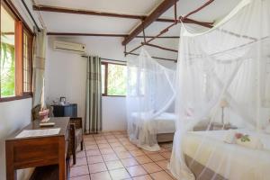 a bedroom with a desk and a bed with mosquito net at LEMON BEACH LODGE Vilankulo in Vilanculos