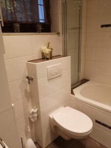 a white bathroom with a toilet and a bath tub at Ruhig gelegenes Ferienhaus in Simmelsdorf